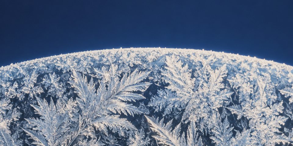 Fern-like frost crystals under a deep blue sky
